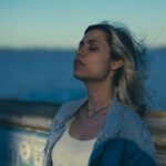 Woman in a denim jacket enjoying a serene moment by the water in Chascomús, Argentina.